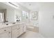 Bright bathroom featuring white cabinets, bathtub with plant, and a window at 1624 Glenfield Dr, Lawrenceville, GA 30043