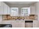 Kitchen featuring white cabinets, tiled backsplash, stainless steel sink and appliances at 1834 Broad Ave, Atlanta, GA 30344
