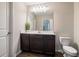 Well-lit bathroom featuring a dark vanity with a sink and mirror, alongside a toilet and ample lighting at 2039 Wildflower Nw Way, Conyers, GA 30012