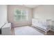 Bright bedroom showcasing a white crib, a dresser, and ample natural light from a window at 2039 Wildflower Nw Way, Conyers, GA 30012