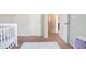 Cozy bedroom with neutral walls and carpet, showcasing a white crib and a doorway to another room at 2039 Wildflower Nw Way, Conyers, GA 30012
