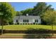 Charming white home with lush green lawn, surrounded by mature trees and a stone retaining wall at 458 Shannon Sw Dr, Atlanta, GA 30310