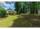 Large, grassy backyard with mature trees, leading up to a house with brick accents at 919 Rock Oak Ln, Lawrenceville, GA 30046