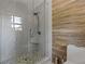Modern tiled shower with pebble flooring, glass door, and wood-look accent wall at 919 Rock Oak Ln, Lawrenceville, GA 30046