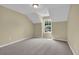 This upper bedroom has neutral-toned walls and carpet with a window overlooking the property's yard at 2988 Belfaire Lake Dr, Dacula, GA 30019