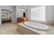 Luxurious bathroom featuring a soaking tub with tile surround and large window for natural light at 3519 Preserve Se Dr, Atlanta, GA 30339