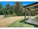 View of the home's backyard, featuring a covered patio and ample green space surrounded by trees at 110 Northwood Creek Way, Oxford, GA 30054