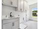 Convenient laundry room with modern sink, plenty of cabinetry, and a bright window at 110 Northwood Creek Way, Oxford, GA 30054