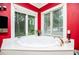 Corner bathtub with jets overlooks the backyard in this red bathroom with a large window at 1050 Denton Rd, Douglasville, GA 30134