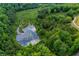 Scenic aerial view of the property showing the pond surrounded by a densely wooded landscape at 1050 Denton Rd, Douglasville, GA 30134