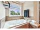Close-up of a bathroom tub under a window with a view, featuring tile surround and a towel set at 3480 Indian Shoals Rd, Dacula, GA 30019