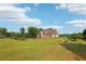 Expansive lawn with a charming brick home featuring a deck, complemented by a clear blue sky at 3480 Indian Shoals Rd, Dacula, GA 30019