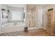 Bright bathroom featuring a soaking tub, glass shower, and wood-look floors at 1017 Preserve Park Dr, Loganville, GA 30052
