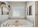 Bright bathroom featuring a soaking tub with decorative tile and shelving above at 1017 Preserve Park Dr, Loganville, GA 30052