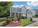 Beautifully landscaped front yard of a two-story home with a covered porch, brick accents, and blue shutters at 1017 Preserve Park Dr, Loganville, GA 30052