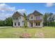 Beautiful two-story home showcasing an inviting front porch and a perfectly manicured green lawn with stone and siding at 157 Haverling Pass, Hampton, GA 30228