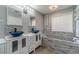 Bathroom featuring dual sinks with blue vessel sinks, white cabinets, and a gray tiled soaking tub at 123 Chippewa Run, Auburn, GA 30011
