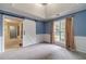 Bright bedroom featuring blue walls, wainscoting, a sliding barn door, and large windows for natural light at 123 Chippewa Run, Auburn, GA 30011