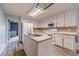 Open kitchen layout with an island, white cabinets, stainless steel appliances, and wood-look floors at 123 Chippewa Run, Auburn, GA 30011