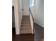Carpeted staircase featuring a stained wood handrail and white risers, offering a classic and safe transition between floors at 3848 Hester St, Duluth, GA 30097