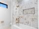 Modern bathroom featuring marble tile surround, gold shower fixtures, and floating shelves at 5370 Greenleaf Sw Dr, Mableton, GA 30126