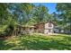 Split-level home with well-kept lawn and a stone accent fence, surrounded by large, mature trees providing ample shade at 5491 Valley Brook Road Southeast Se Rd, Mableton, GA 30126