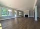 Bright and open living room featuring hardwood floors, a fireplace, and large windows overlooking the lush exterior at 8239 High Lake Ter, Covington, GA 30014
