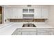 Close up on white cabinets, stainless sink and a backsplash with earth tone colors at 916 Forest Pointe Way, Jonesboro, GA 30238