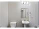 Simple half bathroom featuring a pedestal sink, toilet, and a well-lit mirror in a neutral color palette at 823 Mackay Crk, Woodstock, GA 30188