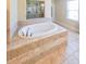 Large soaking tub with tile surround in well-lit bathroom at 265 Enfield Ln, Mcdonough, GA 30252