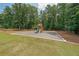 Backyard featuring a playground set surrounded by green grass and a wooded area at 265 Enfield Ln, Mcdonough, GA 30252