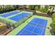 Overhead shot of well-maintained tennis courts with green and blue surfaces, surrounded by fencing at 10000 Barston Ct, Johns Creek, GA 30022