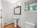 Bright bathroom with a pedestal sink, wood-look flooring, and a framed mirror at 2215 Springdale Sw Rd, Atlanta, GA 30315