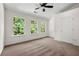Bright bedroom featuring three sunny windows, a ceiling fan, and neutral carpeting at 420 Berckman Nw Dr, Lilburn, GA 30047
