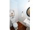 A well-lit half bathroom with hardwood flooring and a decorative round mirror at 550 Quillian Ave, Decatur, GA 30032