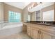 A bright bathroom featuring a soaking tub next to a glass block window and vanity with dark countertops at 1425 Dalewood Ne Dr, Atlanta, GA 30329