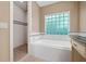 Well-lit bathroom featuring a soaking tub, a glass block window, and a step-in shower at 1425 Dalewood Ne Dr, Atlanta, GA 30329