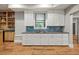 Basement wet bar with white cabinets, blue backsplash, and wood-look flooring at 2230 Ewing Chapel Rd, Dacula, GA 30019