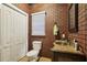 Quaint bathroom with a brick accent wall, a vanity with mirror, and a toilet at 315 Glengarry Chase, Covington, GA 30014