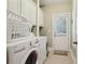 Well-lit laundry room features white cabinets, neutral tile flooring and direct access to the outside at 315 Glengarry Chase, Covington, GA 30014