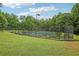 Community tennis court surrounded by mature trees with fence and walkway at 315 Glengarry Chase, Covington, GA 30014