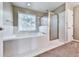 Bright bathroom features a soaking tub, shower with glass door, and white tile at 4601 Ethel Springs Sw Trl, Mableton, GA 30126