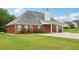 Back exterior of a brick house with a covered patio, well-maintained lawn, and landscaped garden beds at 2825 Ellenwood Village Way, Ellenwood, GA 30294