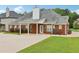 Back exterior view of a brick house with a covered porch, lawn, and manicured rose bushes at 2825 Ellenwood Village Way, Ellenwood, GA 30294