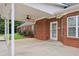 Covered brick back porch, featuring a ceiling fan, and a view of the yard with blooming rose bushes at 2825 Ellenwood Village Way, Ellenwood, GA 30294
