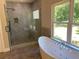 Modern bathroom with a freestanding tub, glass shower, and large window showcasing natural light at 5950 Lynfield Dr, Atlanta, GA 30349