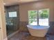 Modern bathroom with a freestanding tub, glass shower, and large window showcasing natural light at 5950 Lynfield Dr, Atlanta, GA 30349