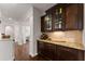 Butler pantry with wood cabinets, granite countertops, and backsplash in hallway with decorative columns at 4022 Roberts Crest Dr, Suwanee, GA 30024
