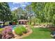Lush backyard featuring a sparkling pool, gazebo, stone patio and meticulously landscaped lawn with mature trees and bushes at 3903 Hazelhurst Dr, Marietta, GA 30066