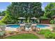 Backyard in-ground pool featuring a stone deck, lounge chairs, umbrellas, and meticulously landscaped surroundings at 3903 Hazelhurst Dr, Marietta, GA 30066